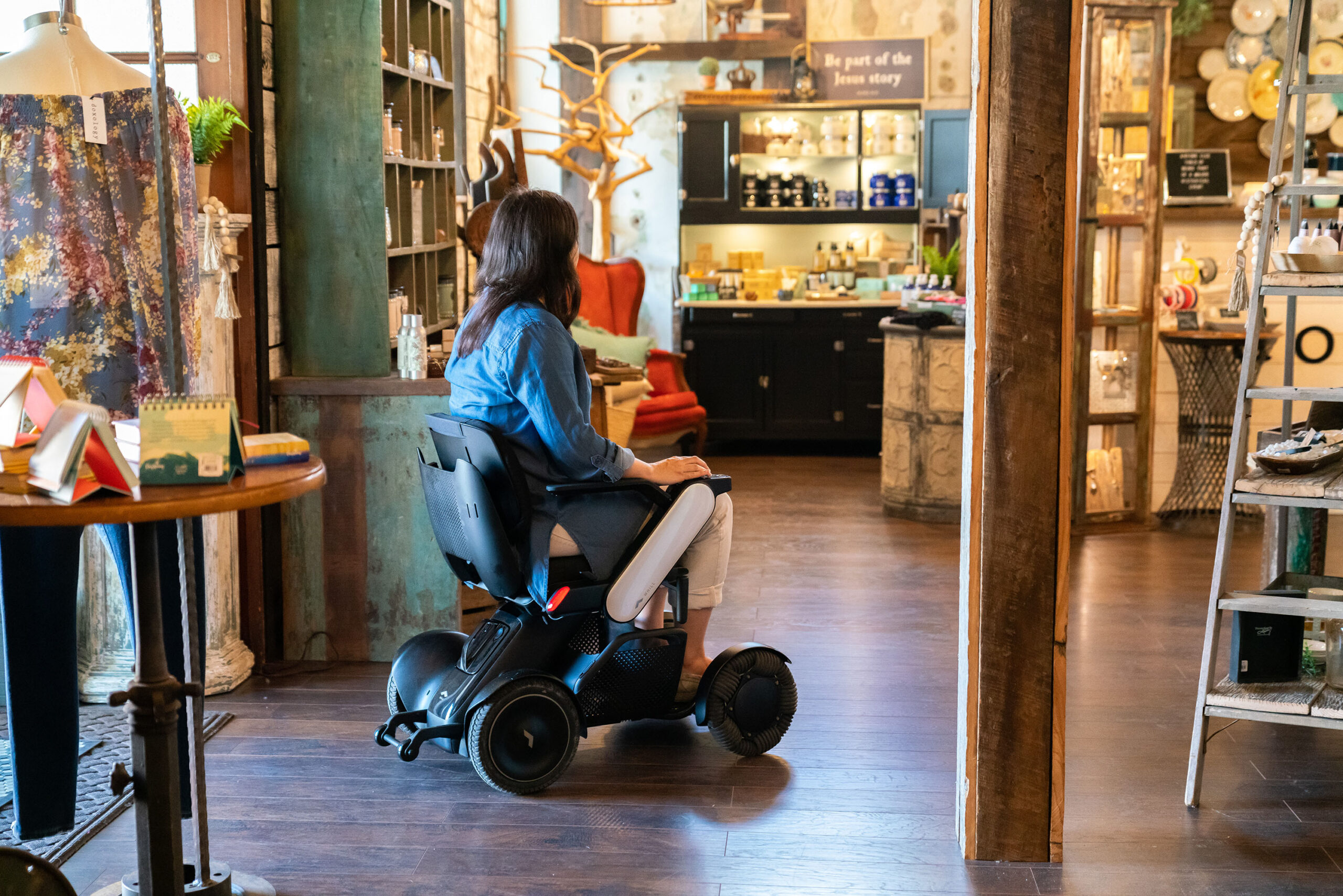 woman entering a store riding a WHILL scooter