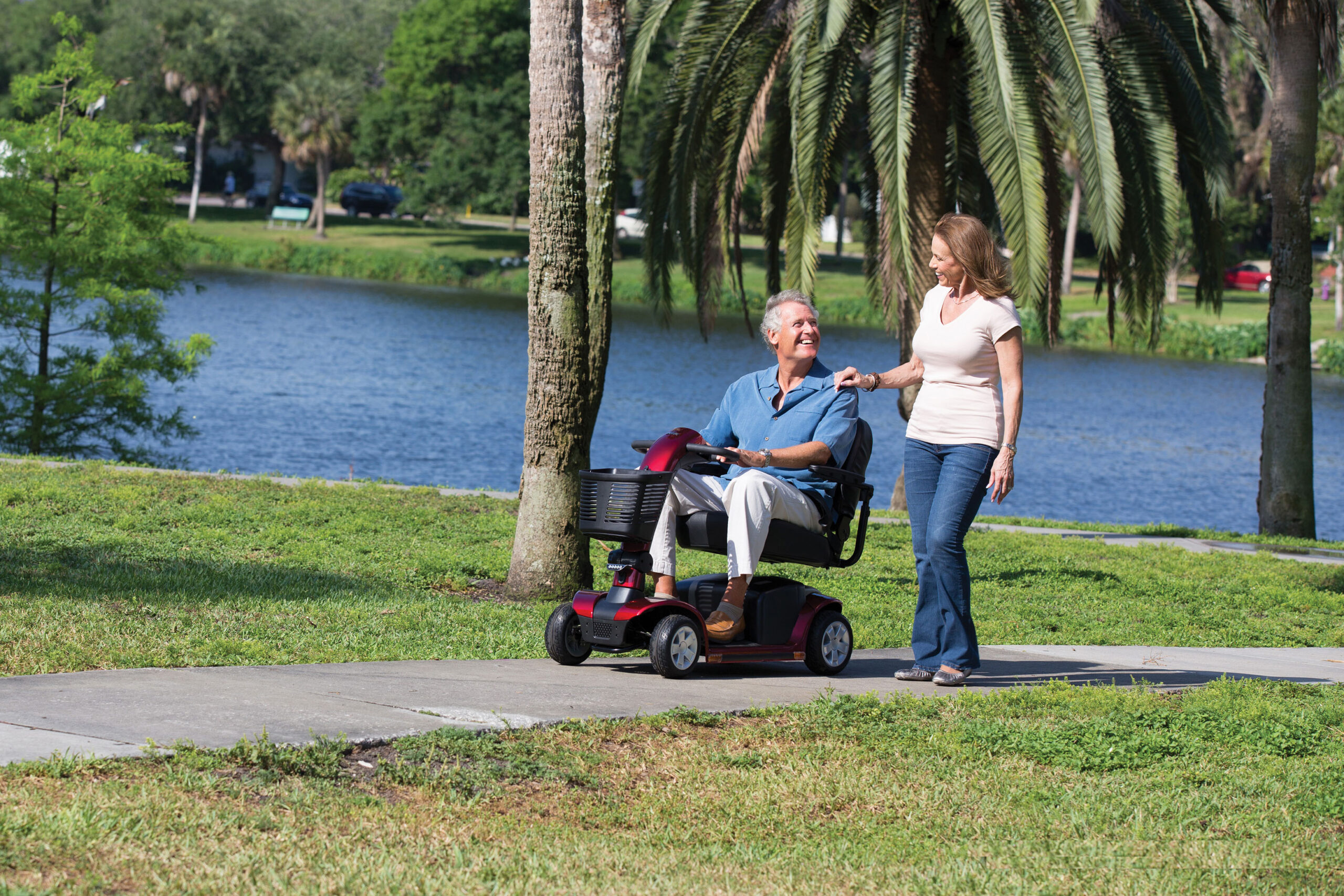 man on a mobility scooter with a woman walking next to him